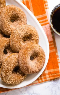 a plate full of doughnuts on a table next to a cup of coffee