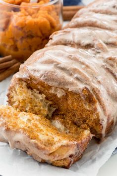 a loaf of cinnamon bread with icing on it and some nuts in the background