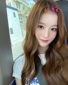 a girl with long brown hair and colorful clips in her hair looking at the camera