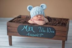 a baby sleeping in a crate with a hat on