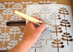 a person using a brush to paint flowers on a piece of paper with stencils