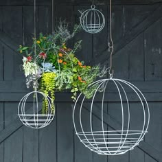 two hanging planters with plants in them on the side of a garage door,