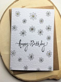 a happy birthday card with daisies and the words happy birthday written on it in black ink