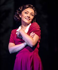 a woman in a red dress standing with her arms crossed