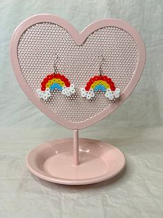 a pair of pink heart shaped earrings with rainbows and clouds hanging from the center