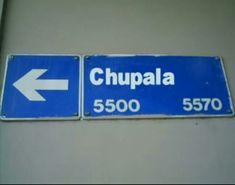 two street signs pointing in opposite directions on a building's wall, one with the word chupala and the other with an arrow