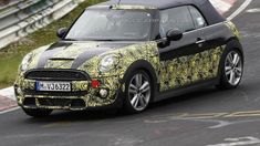 the new mini convertible is shown driving on a race track with yellow and black paint