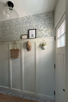 a room with white paneling and blue wallpaper on the walls, two baskets hanging from hooks