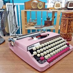 an old pink typewriter sitting on top of a wooden table