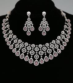 a necklace and earring set with pink stones on a black mannequins