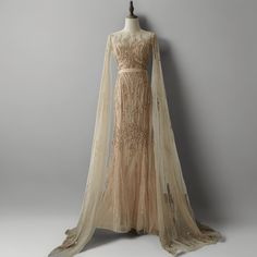 an evening gown on display in front of a gray wall with a long veil over it