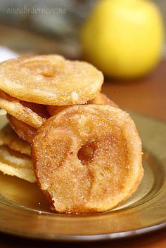 some fried food is stacked on top of each other in a plate with lemons behind it