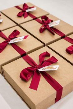 four brown boxes wrapped in red ribbon and with tags on them that say, here they are