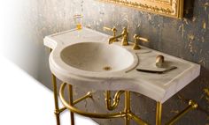 a white sink sitting under a mirror next to a gold faucet in a bathroom