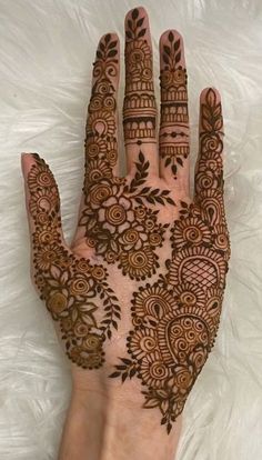 the hand is decorated with henna and flowers on top of white furnishing