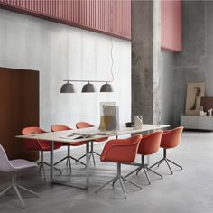 a table with chairs and a laptop on it in an empty room next to a wall