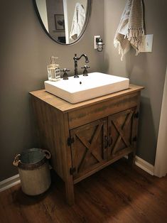 a bathroom with a sink, mirror and towel hanging on the wall next to a trash can