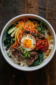 Bibimbap bowl with rice, beef, carrots, cucumbers, spinach, gochujang, and a fried egg, topped with sesame seeds and scallions. Lunch Korean Food, Easy Bibimbap Bowl, Korean Simple Food, Korean Bimbap Bowls, Bimibap Recipes, Dinner Recipes Korean, Lunch Asian, Foods Korean, Bibimpab Korean