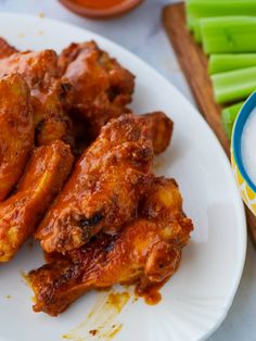 some chicken wings are on a plate next to celery sticks and a bowl of ranch dressing