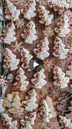 cookies decorated with white frosting and christmas decorations are on a cooling rack, surrounded by other holiday treats