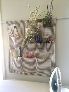 an ironing board with scissors, flowers and other items hanging on it's side