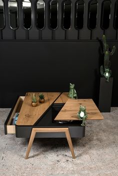 two wooden tables with plants on them in front of a black wall and planters