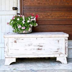 a potted plant sitting on top of a white bench next to a wooden door