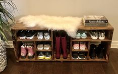 a wooden shoe rack filled with pairs of shoes and a white fluffy rug on top of it