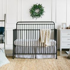 a baby crib in a white room with a wreath on the wall above it