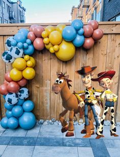 two toy story characters are standing in front of a balloon arch with balloons attached to it