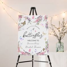 a welcome sign on an easel with flowers and butterflies