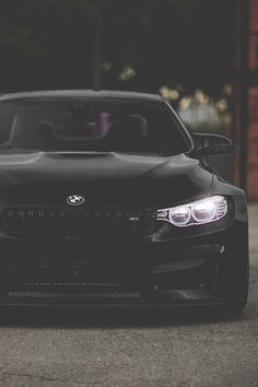 the front end of a black car parked in a parking lot