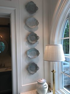 plates are hanging on the wall next to a table with a lamp and vase in front of it