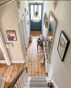 an overhead view of a hallway with stairs and pictures on the wall, flowers in vases