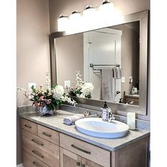 a bathroom with a sink, mirror and flowers on the counter