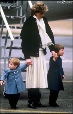 a woman and two children walking towards an airplane