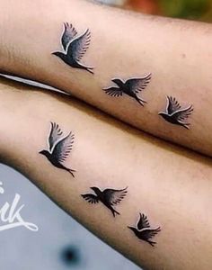 two people with matching tattoos on their arms, one has a bird and the other has a dove