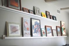 there are many framed pictures on the wall above the couch in this living room area