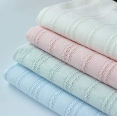 four different colors of towels stacked on top of each other, with the same size