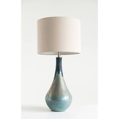 a table lamp with a white shade on it and a blue vase in the foreground