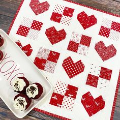 red and white heart shaped pastries on a plate next to a quilted table runner