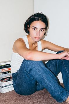 a woman is sitting on the floor with her legs crossed and looking at the camera