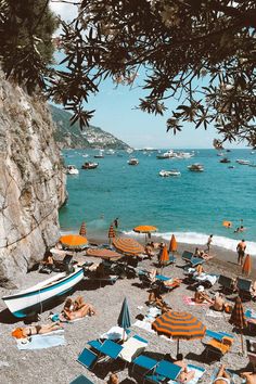 many people are laying on the beach with umbrellas