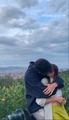 two people embracing each other in the middle of a field full of wildflowers