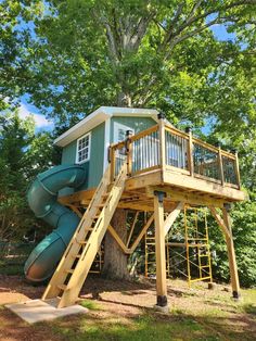 a tree house with a slide in the middle and a deck on top that is attached to it