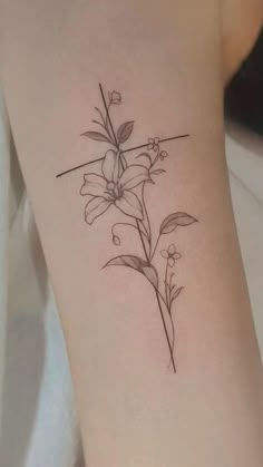 a small tattoo with flowers on the side of the arm and behind it is a cross