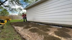 a woman is shoveling dirt in front of a house