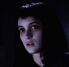 a woman with long black hair standing in the dark