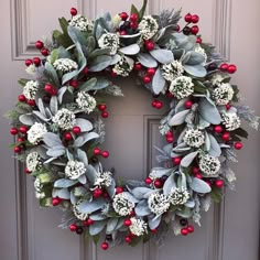 a wreath with red berries and greenery on the front door