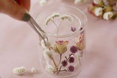 a person cutting flowers into small glass vases on a pink tablecloth with cotton floss